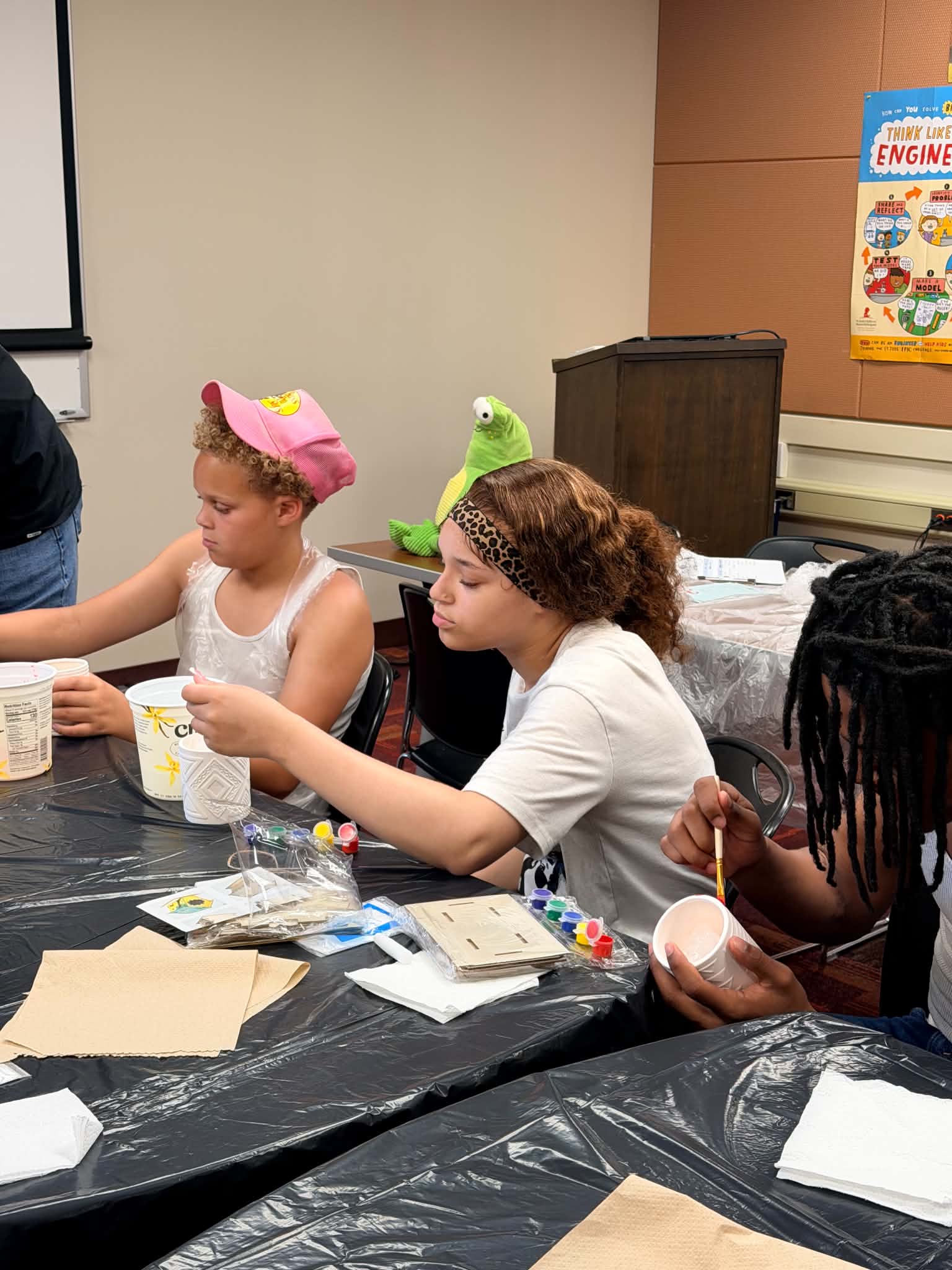 Young participants painting and decorating wooden art pieces during a Rising Up Now workshop.