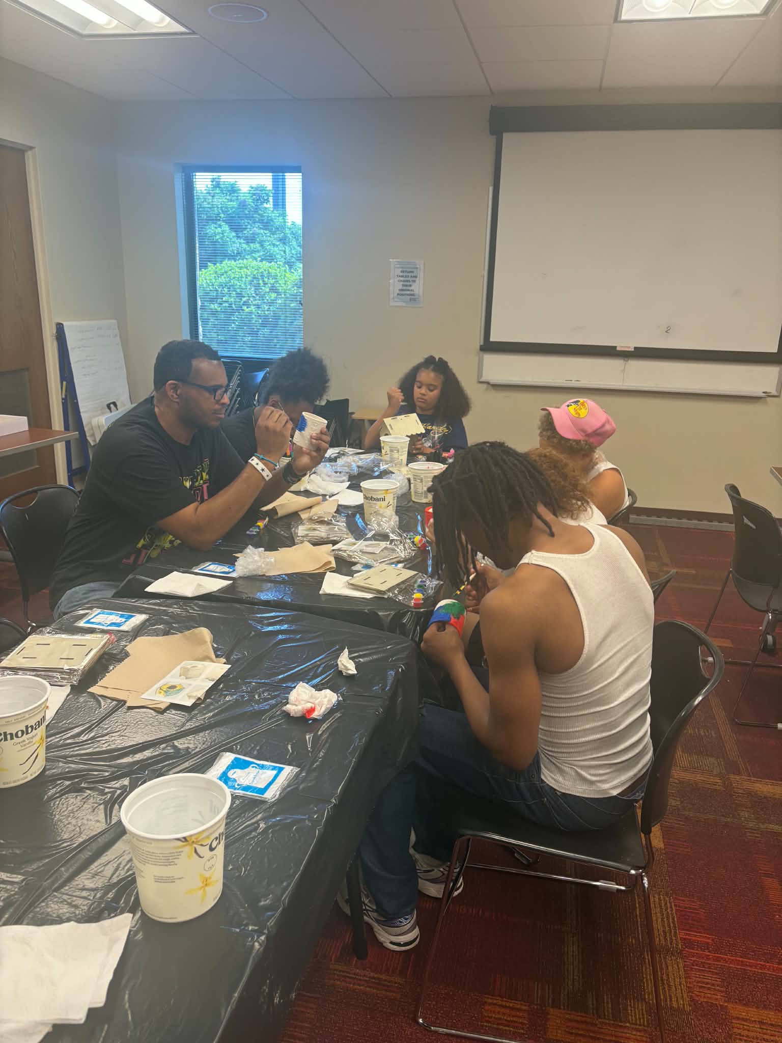 Participants seated around a long table during a collaborative art workshop.