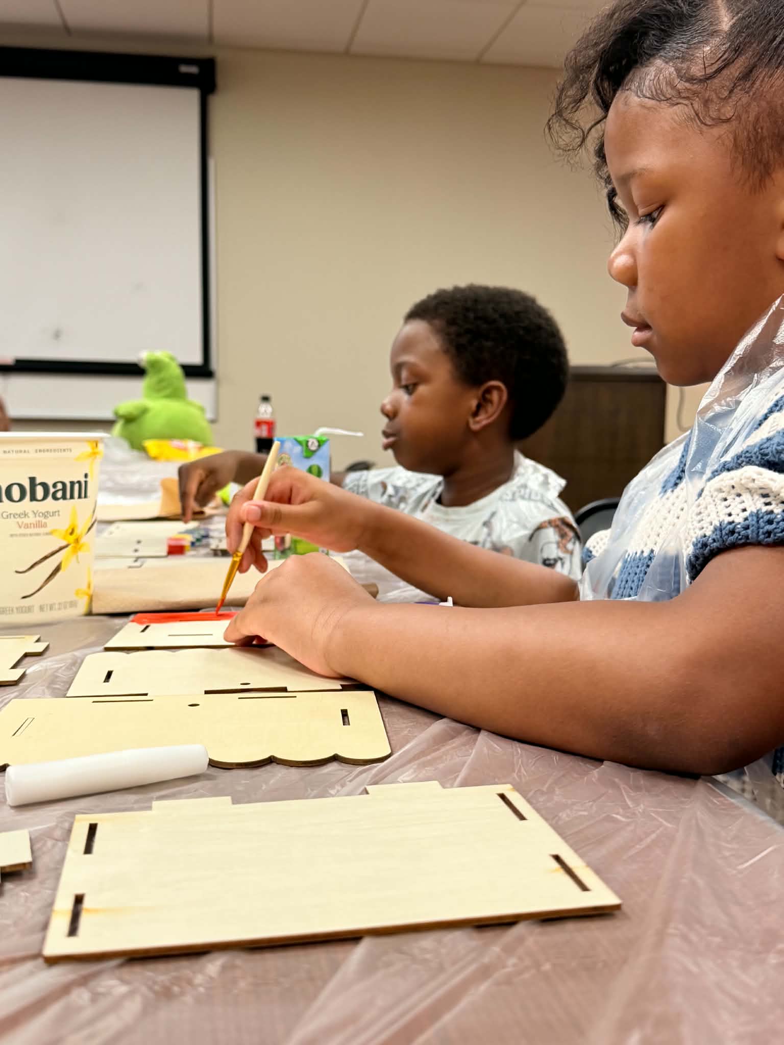 Participants painting wooden art pieces during a close-up workshop moment.