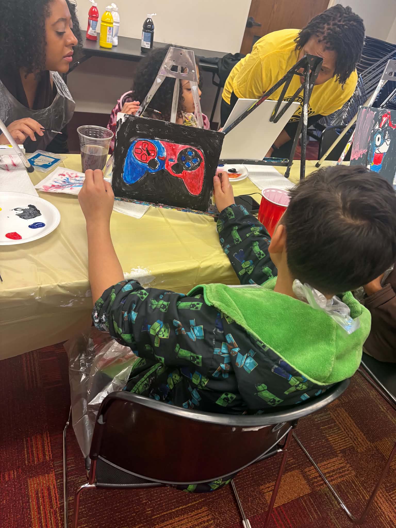 Children painting at tabletop easels during a Rising Up Now art workshop.