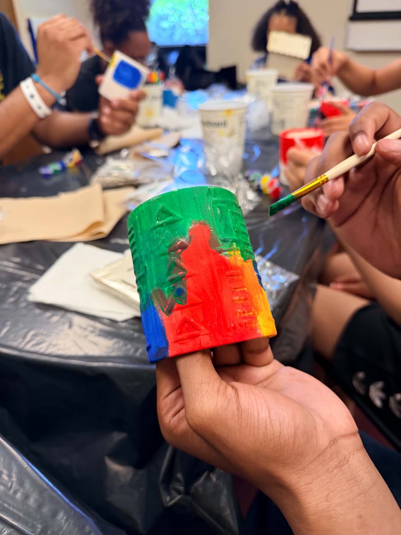 A close-up of a colorful painted art project being held during a workshop.