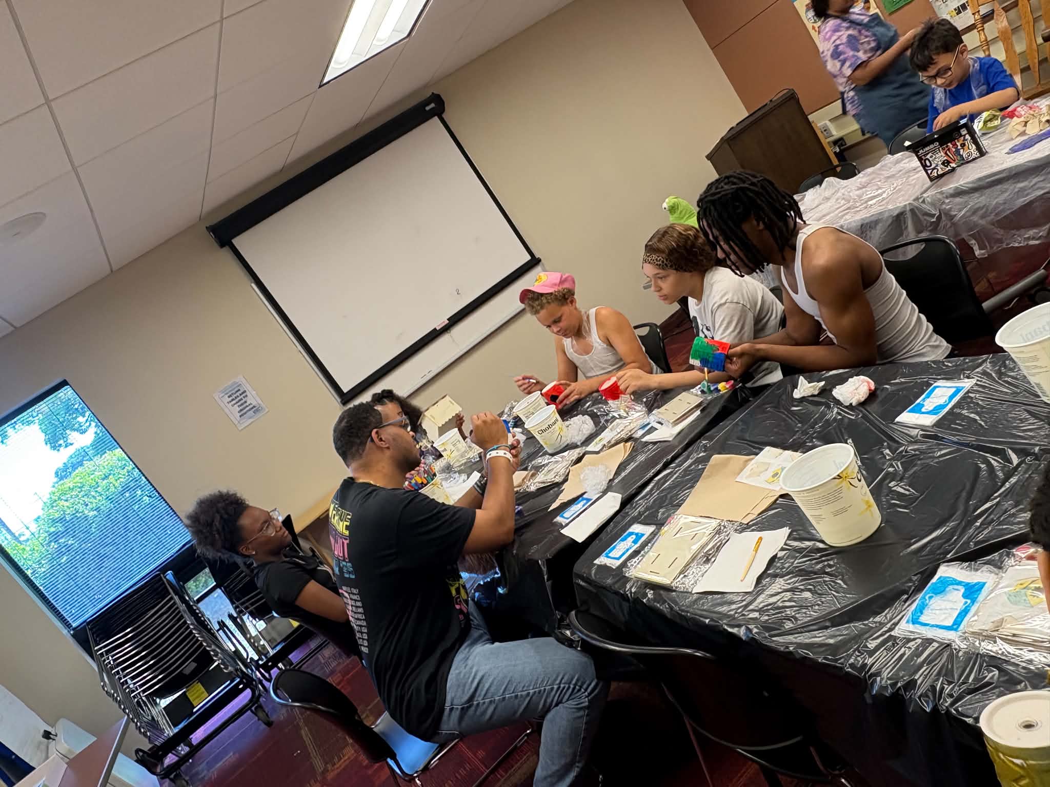 Participants and facilitators gathered around tables during a Rising Up Now art workshop session.