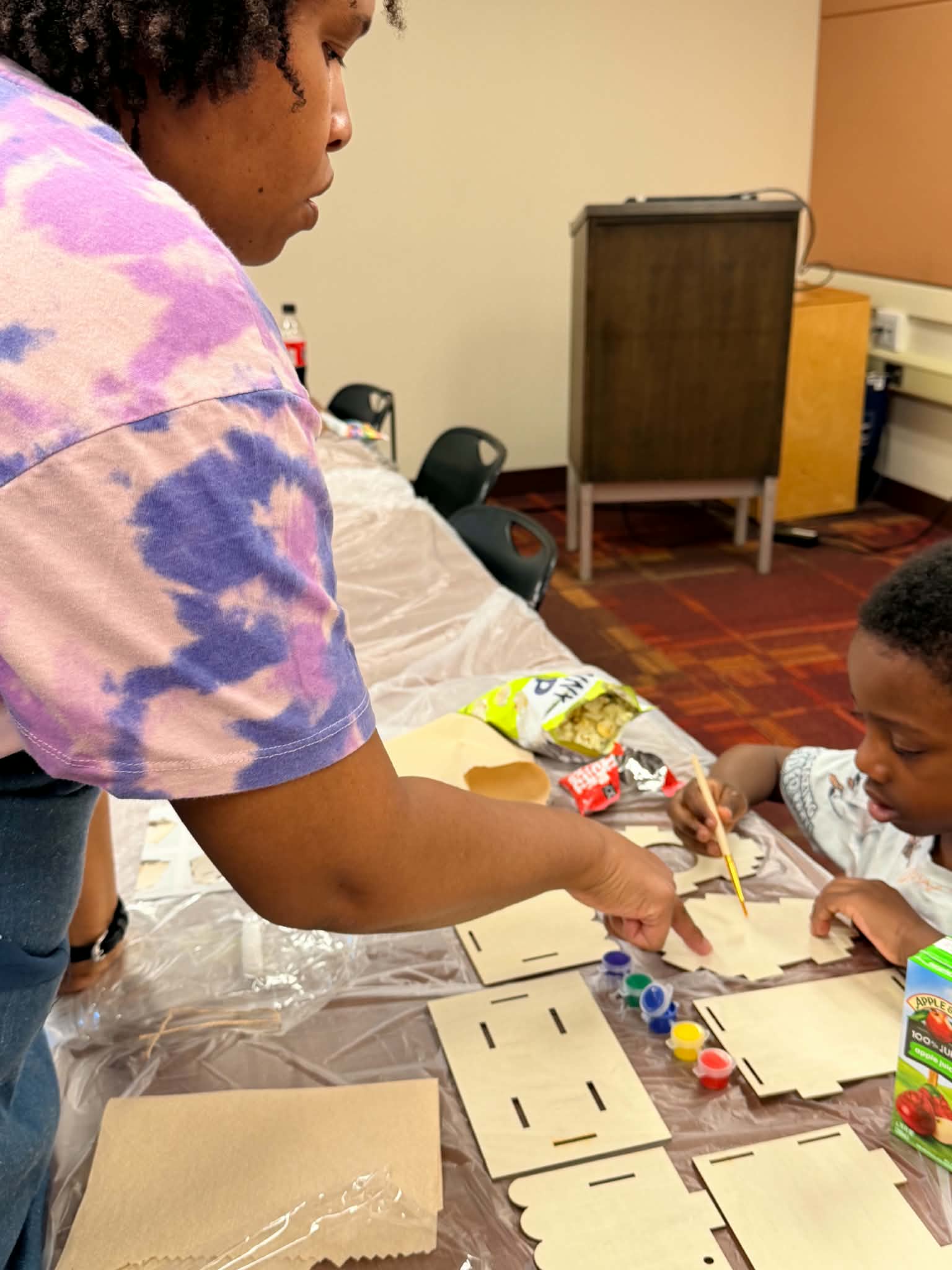 A facilitator moving around the table while children continue their workshop projects.